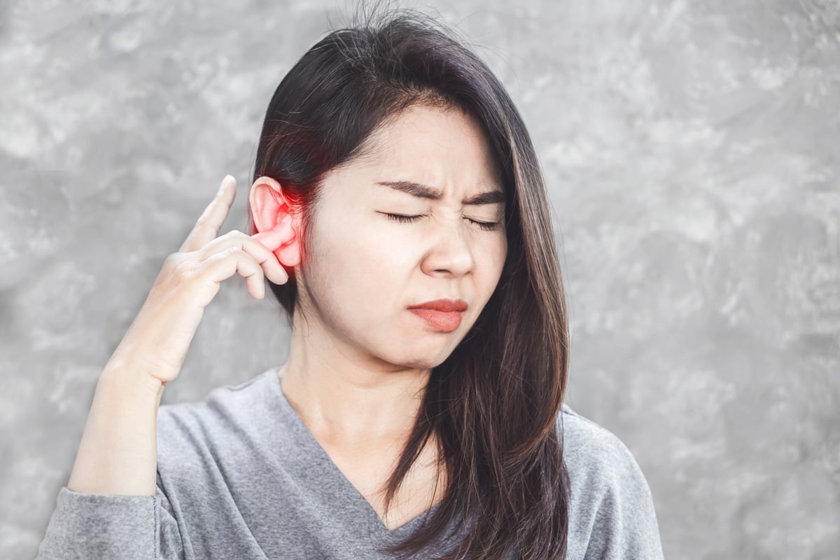 an Asian woman having problems with tinnitus and ear pain